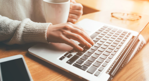 woman typing at laptop with coffee