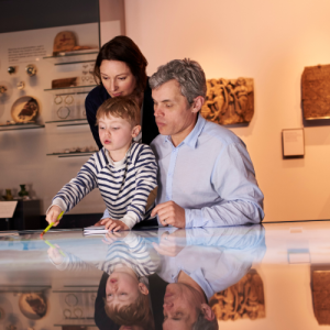 Parents and their child explore an interactive touchscreen at a museum.