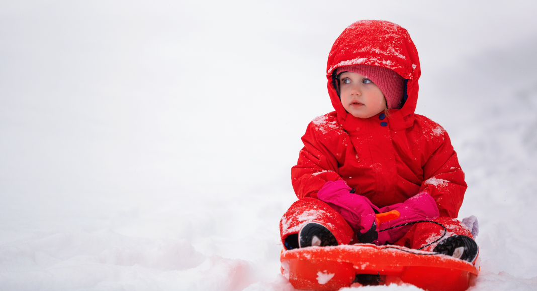 toddler bundled up on a sled