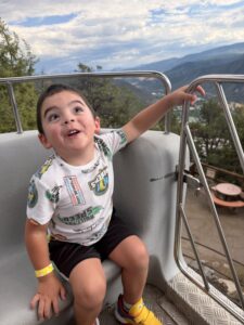 Young boy riding the Mine Wheel at Glenwood Caverns Adventure Park with panoramic mountain views overlooking Glenwood Springs.
