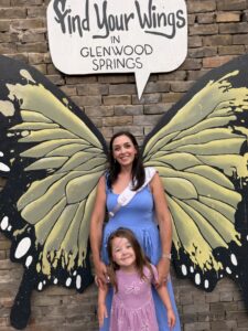 A mother and young daughter pose in front of the “Find Your Wings” butterfly mural in downtown Glenwood Springs, Colorado.
