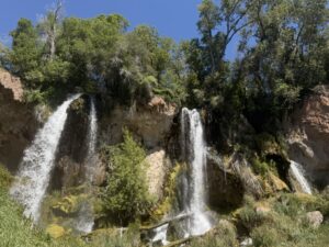 The triple waterfalls at Rifle Falls State Park cascade over limestone cliffs surrounded by lush greenery in Rifle, Colorado.